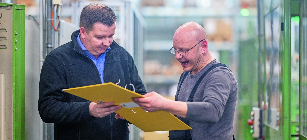 Produktionsleiter Jens Böttcher und Frank Neumann prüfen die Mechanik eines Ordners.